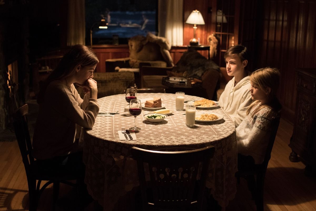 A woman sits across from two children.