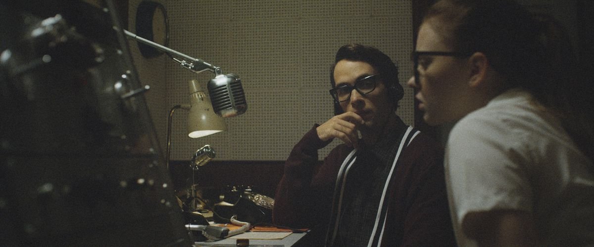 Jake Horowitz and Sierra McCormick sit in front of a 1950s microphone at the radio station in The Vast of Night