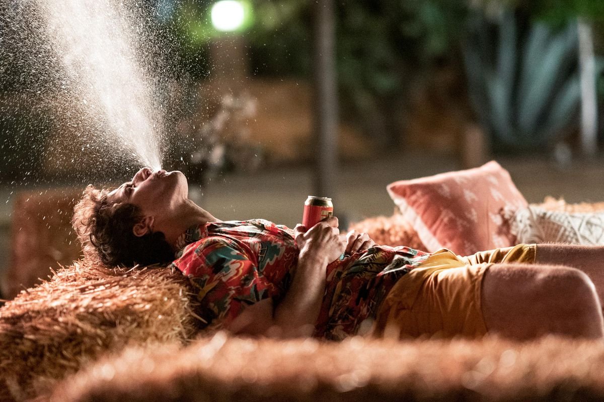 Andy Samburg spits a spray of beer into the air while lying on his back in Palm Springs.