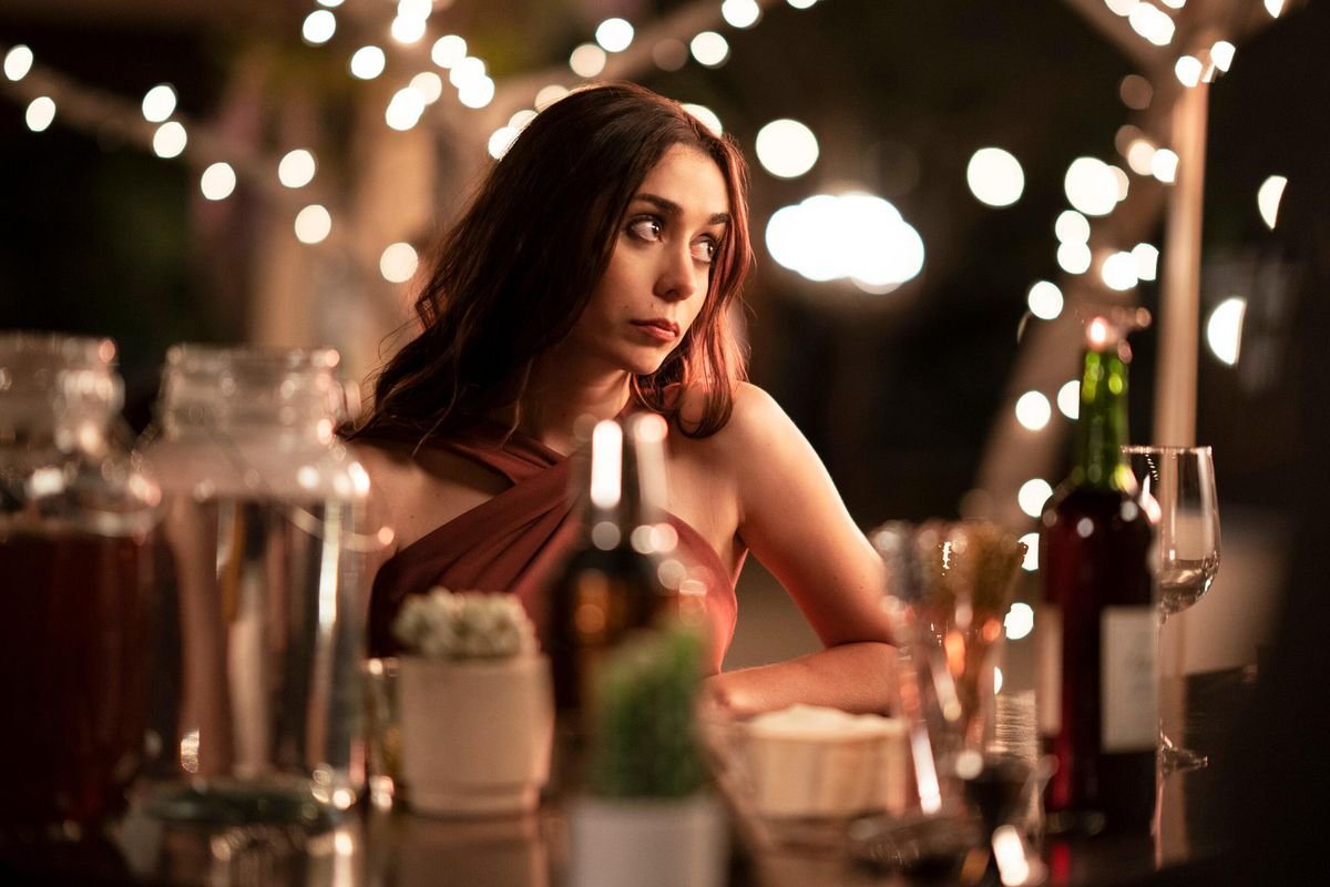 Cristin Milioti, sitting among string lights at a wedding reception, rolls her eyes at something offscreen in Palm Springs.