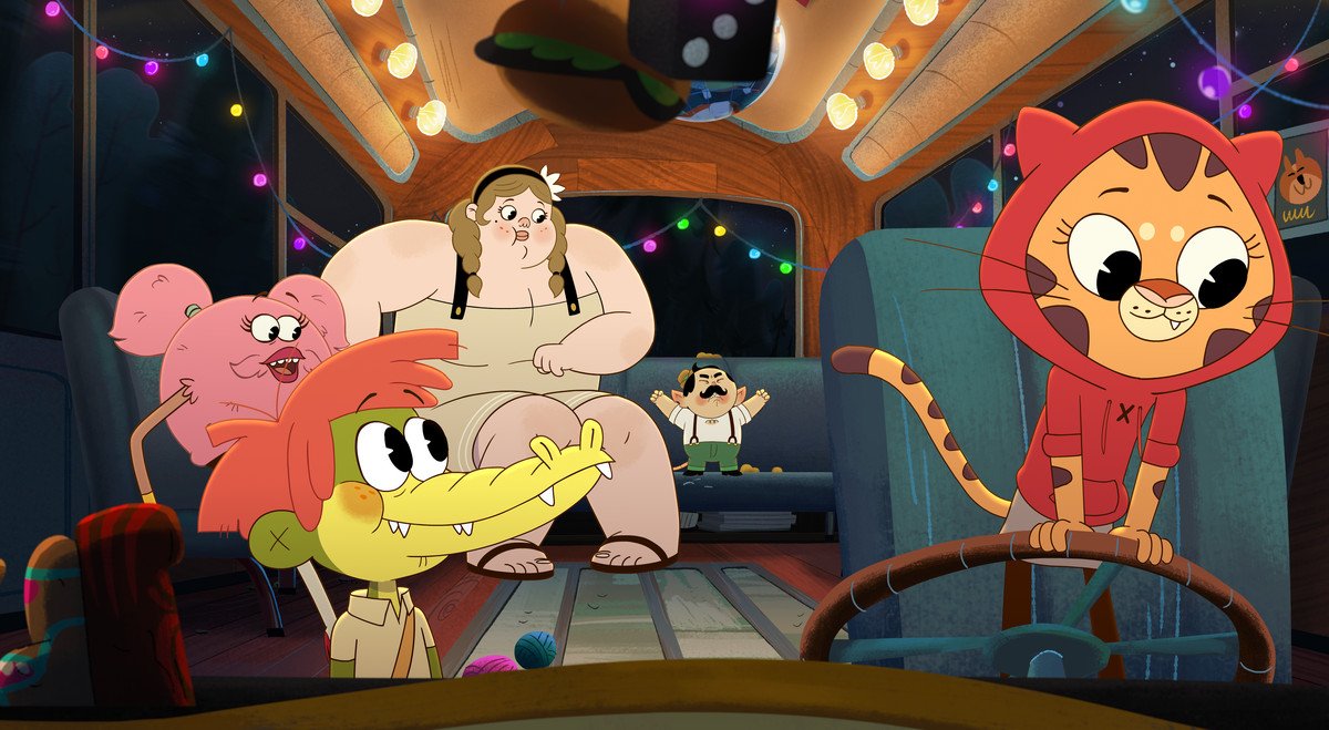 Alia, a tiger girl in a red hoodie, driving a bus, with Arlo the alligator boy in the passenger’s seat. Behind them are Bertie, a large woman, and Furlecia, a sentient pink hairball, and tiny man Tony.