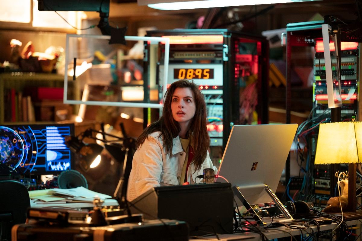 Anne Hathaway sits surrounded by junky-looking electronics up to the ceiling in Solos