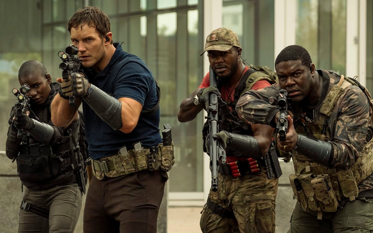 Chris Pratt stands meaningfully at the head of a small group of armed and camo-wearing soldiers, all of whom are Black except him