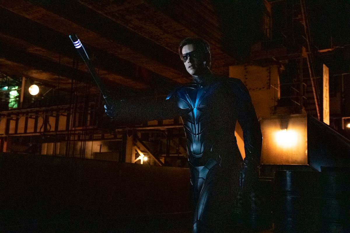 Brenton Thwaites as Robin in Titans season 3, holding up a glowing baton in a warning gesture