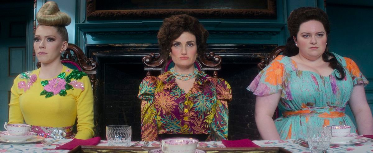 Cinderella’s stepmother (Idina Menzel) and stepsisters sit in a line looking grouchy in Amazon’s Cinderella