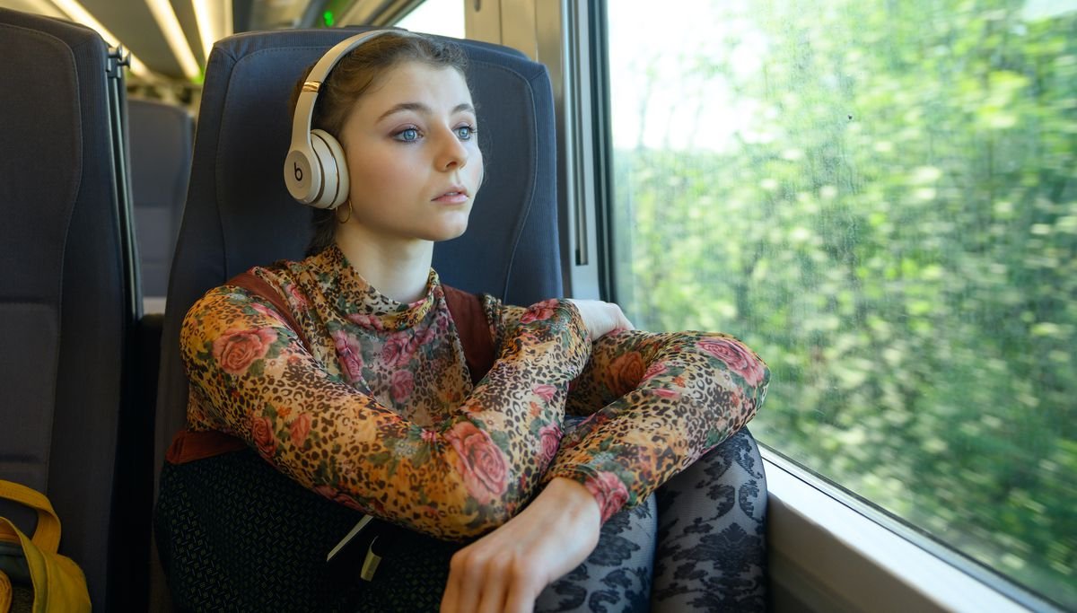 Thomasin McKenzie, curled around herself on the train to London, in Last Night in Soho