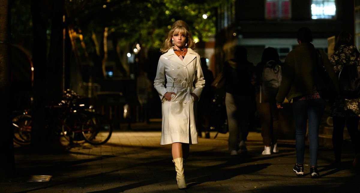 Anya Taylor-Joy, in a bright white coat, walks the dark streets of Soho in Last Night in Soho