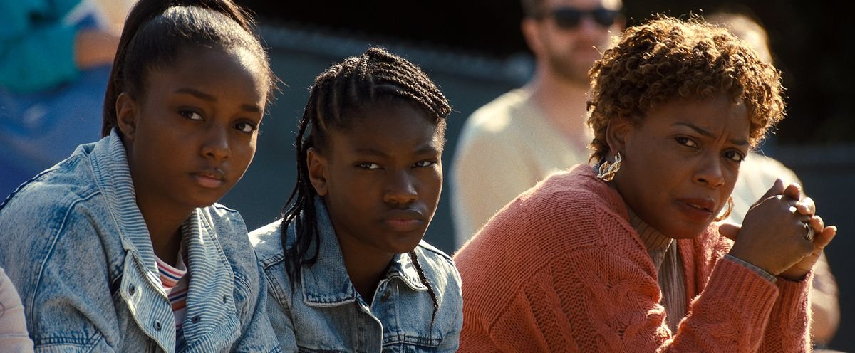 DANIELE LAWSON as Isha Price, DEMI SINGLETON as Serena Williams and AUNJANUE ELLIS as Oracene “Brandy” Williams sit courtside and glower in King Richard