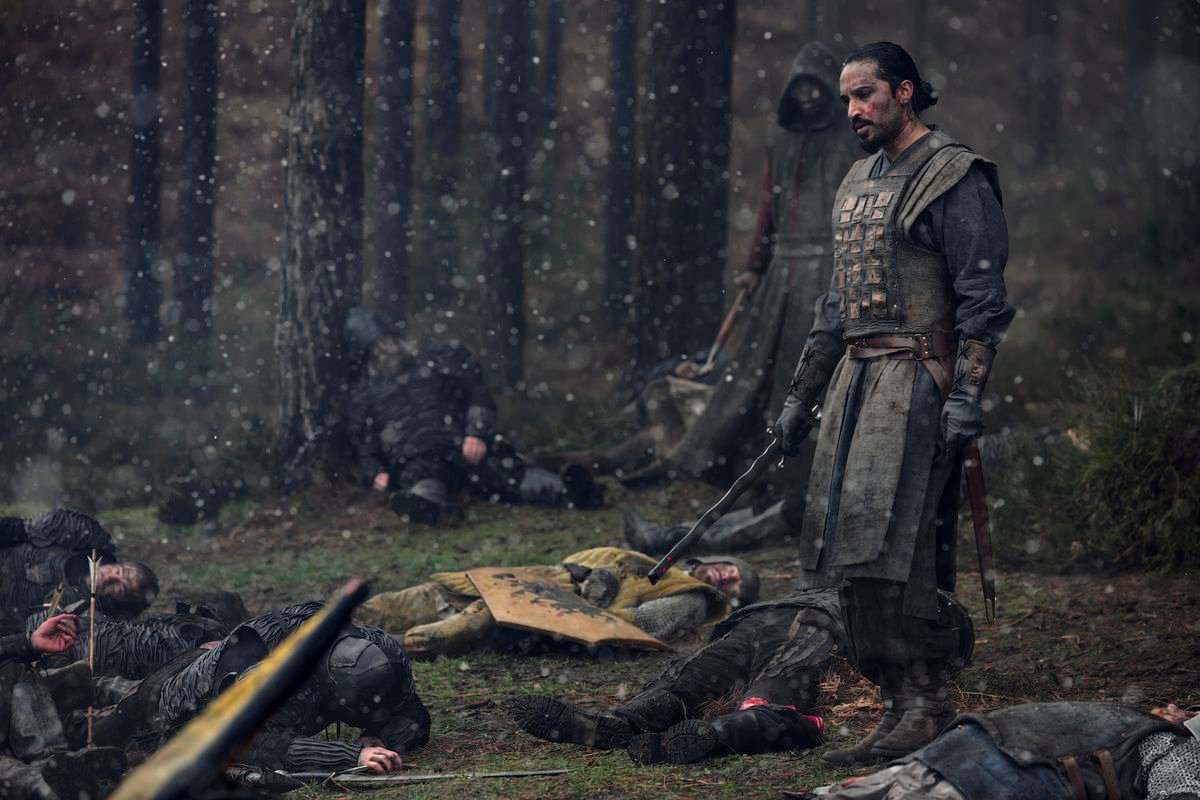 A soldier stands over a snowy battlefield of other dead soldiers in Netflix’s The Witcher