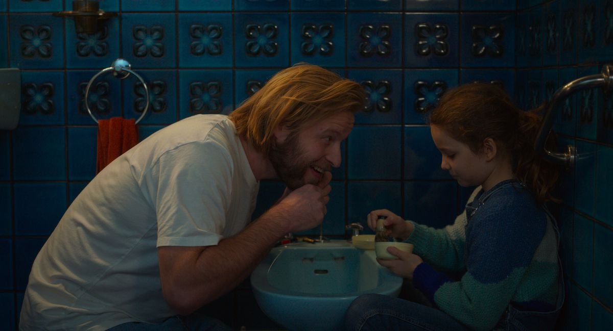 Eight-year-old Nelly and her father sit together in the bathroom in Petite Maman