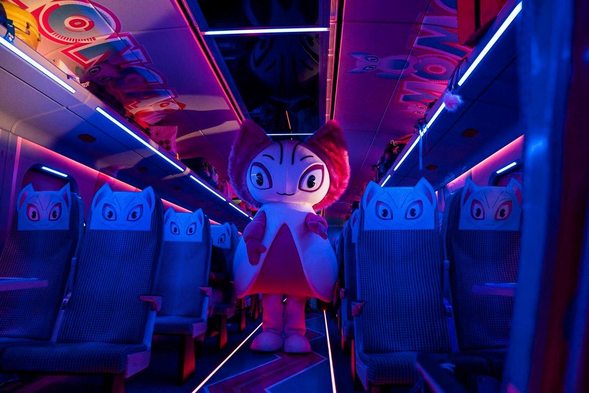 A mascot stands in the neon lit gangway of an empty car in Bullet Train.