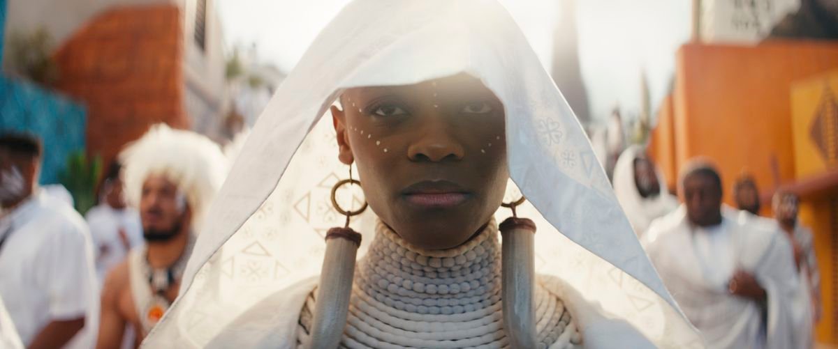 Shuri (Letitia Wright) adorned in a white funeral shawl with wearing long ivory earrings in Black Panther: Wakanda Forever