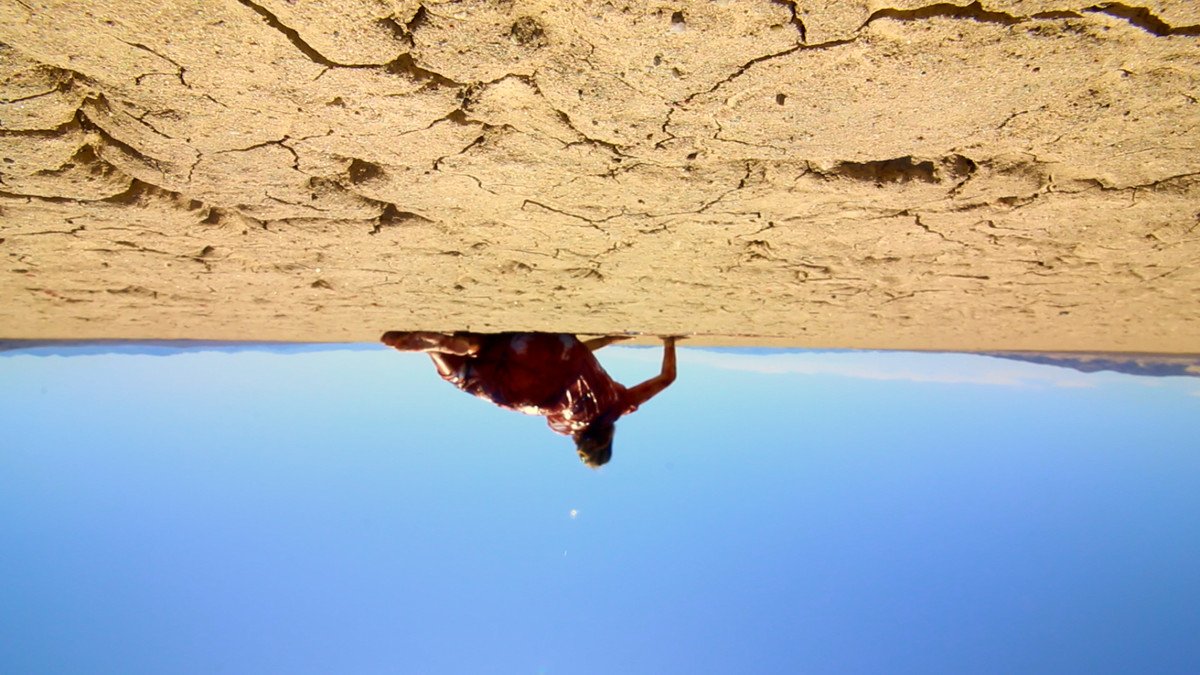 A character from The Outwaters lies in the desert with bloody clothes in an upside-down shot