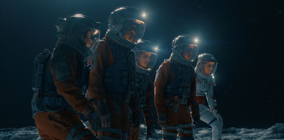 Five teenagers in space suits walking across the surface of the moon. 