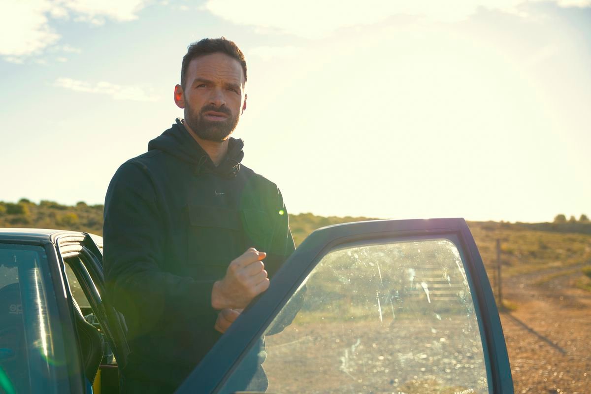 Alban Lenoir makes a fist with his hand on an open car door in Lost Bullet 2