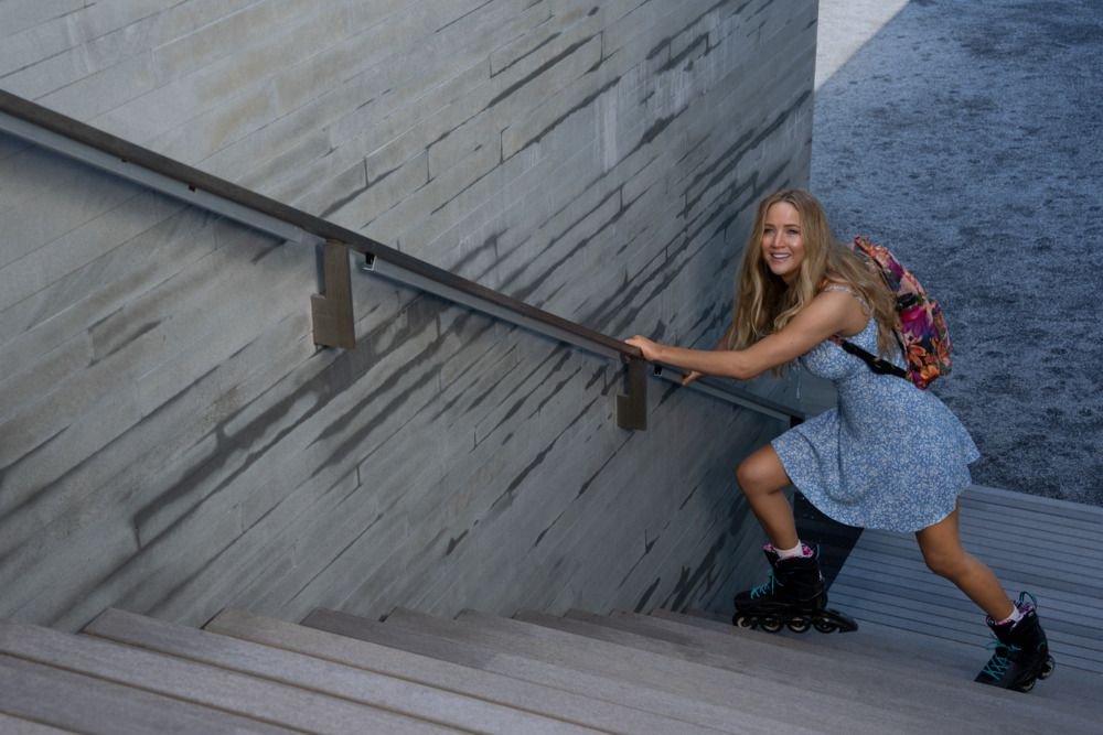 Jennifer Lawrence attempts to climb a set of stairs in roller blades while clutching the bannister in the film No Hard Feelings.