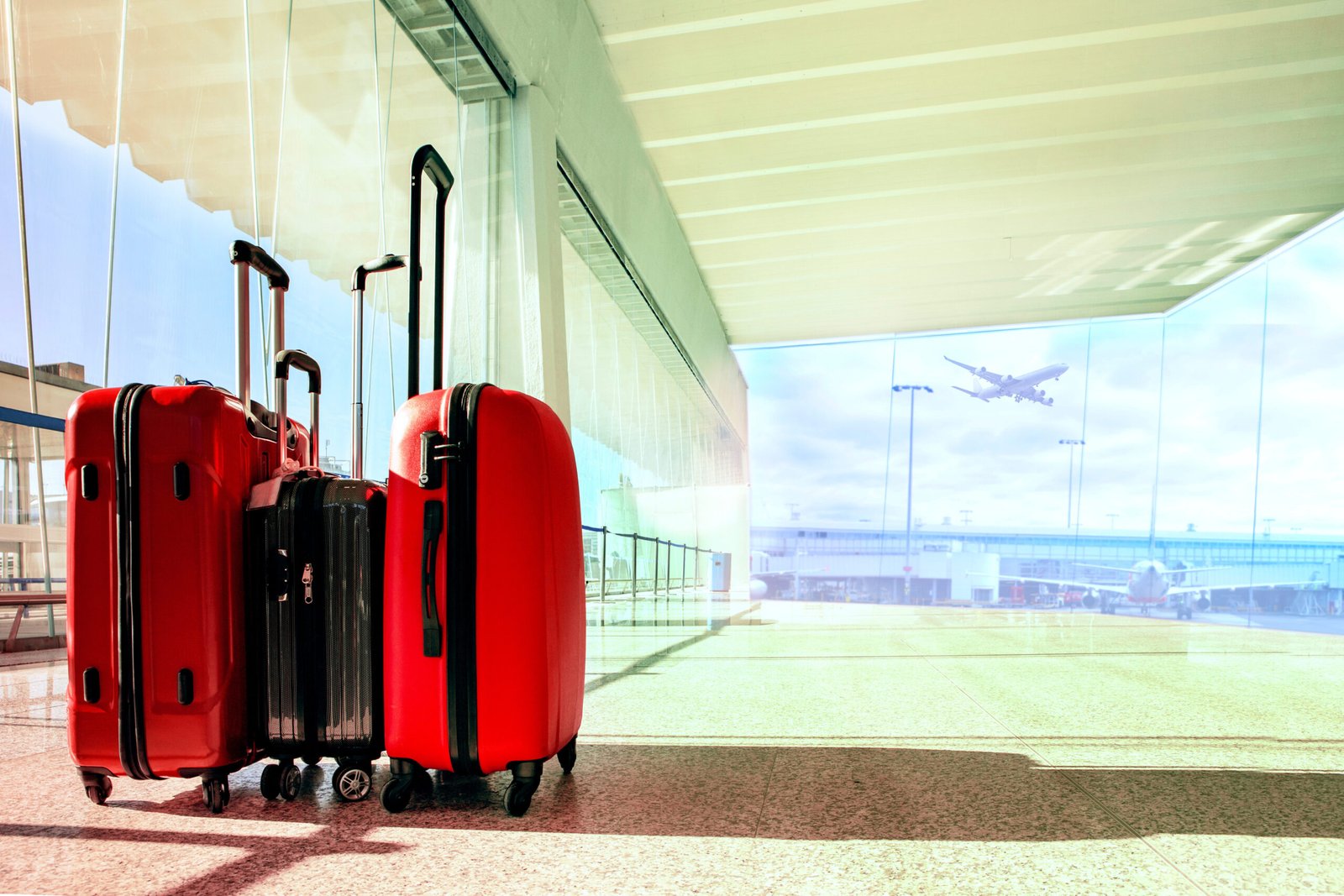 Luggage at airport terminal with plane taking off in the background