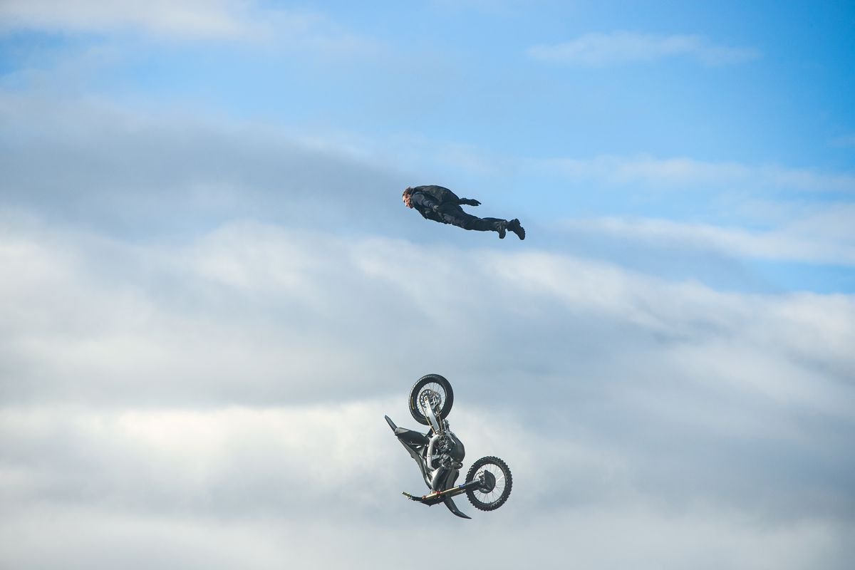 Tom Cruise soars in the sky as the motorcycle he was on plunges to the clouds below them in Mission: Impossible — Dead Reckoning Part 1