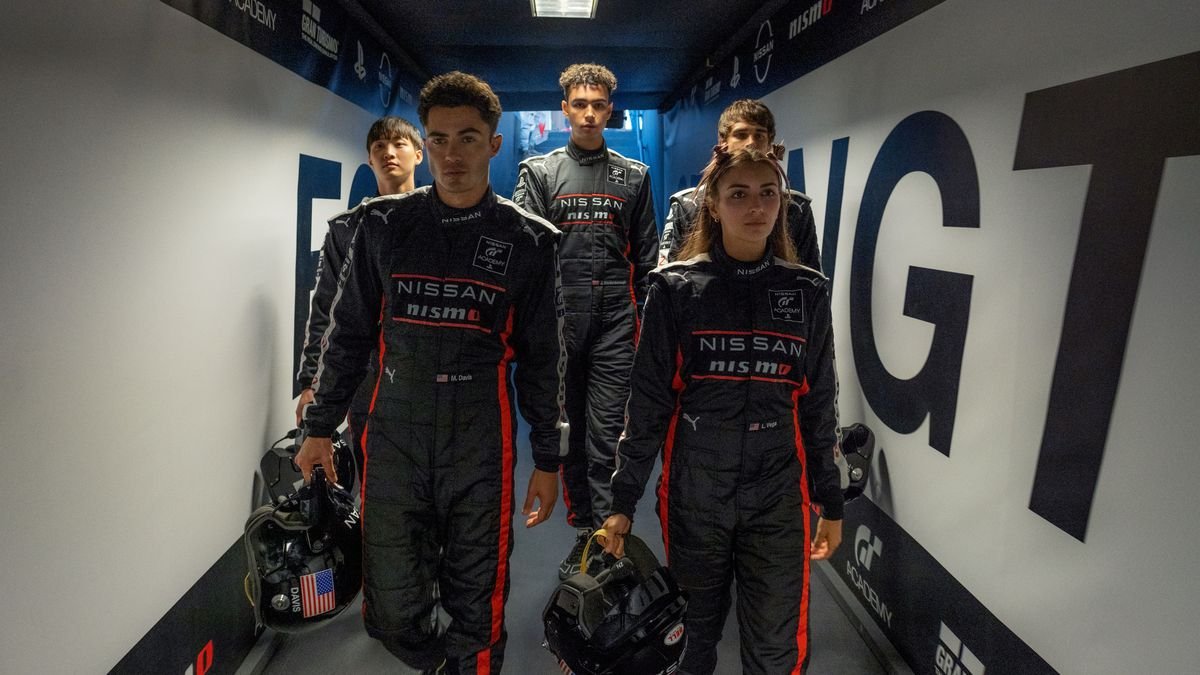 A team of young racers wearing overalls walk down a corridor in the Gran Turismo movie