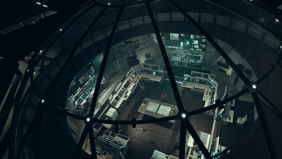in a screenshot from Starfield, the camera looks into a space station from overhead, through a glass dome; a man is sitting at a table surrounded by lots of equipment