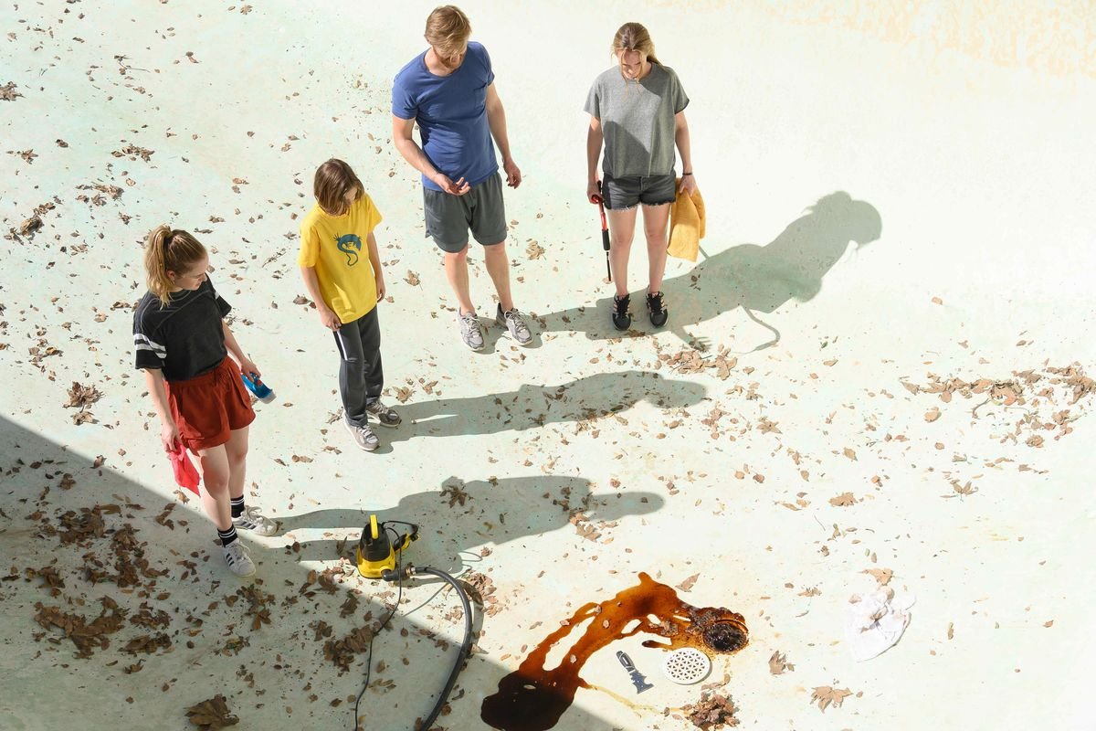 Amélie Hoeferle, Gavin Warren, Wyatt Russell, and Kerry Condon stand in a pool surrounded by blood and grime in Night Swim