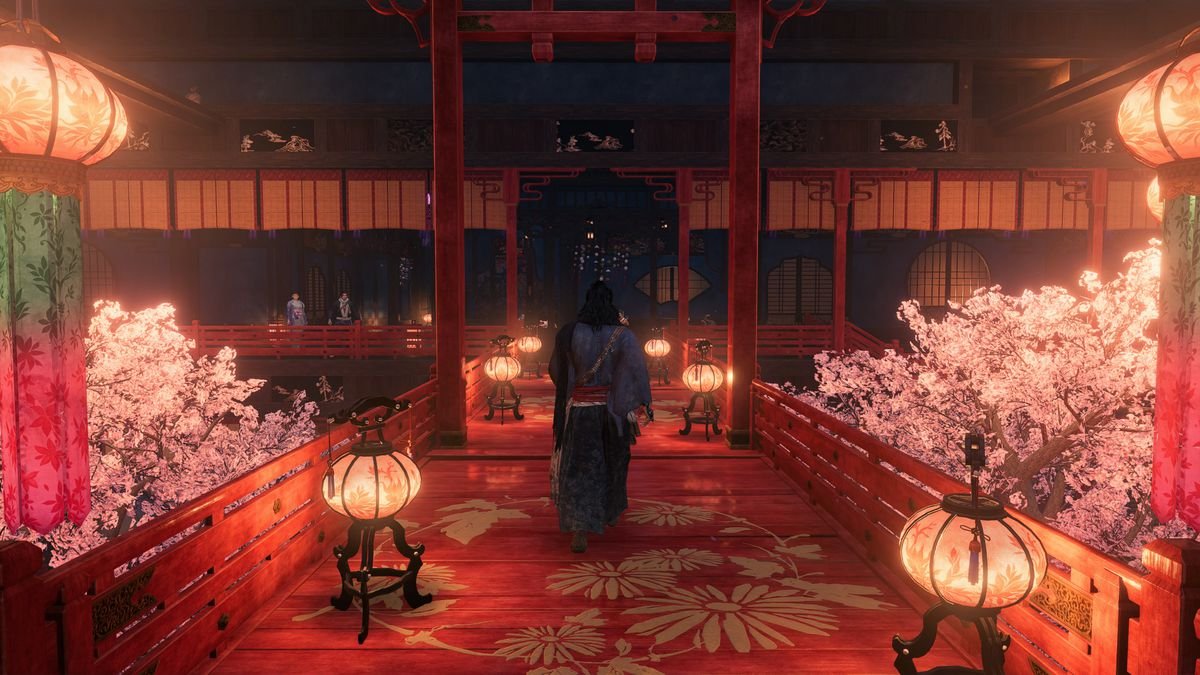 A player character walking across an elaborate red  painted bridge flanked by lanterns and cherry blossom trees.