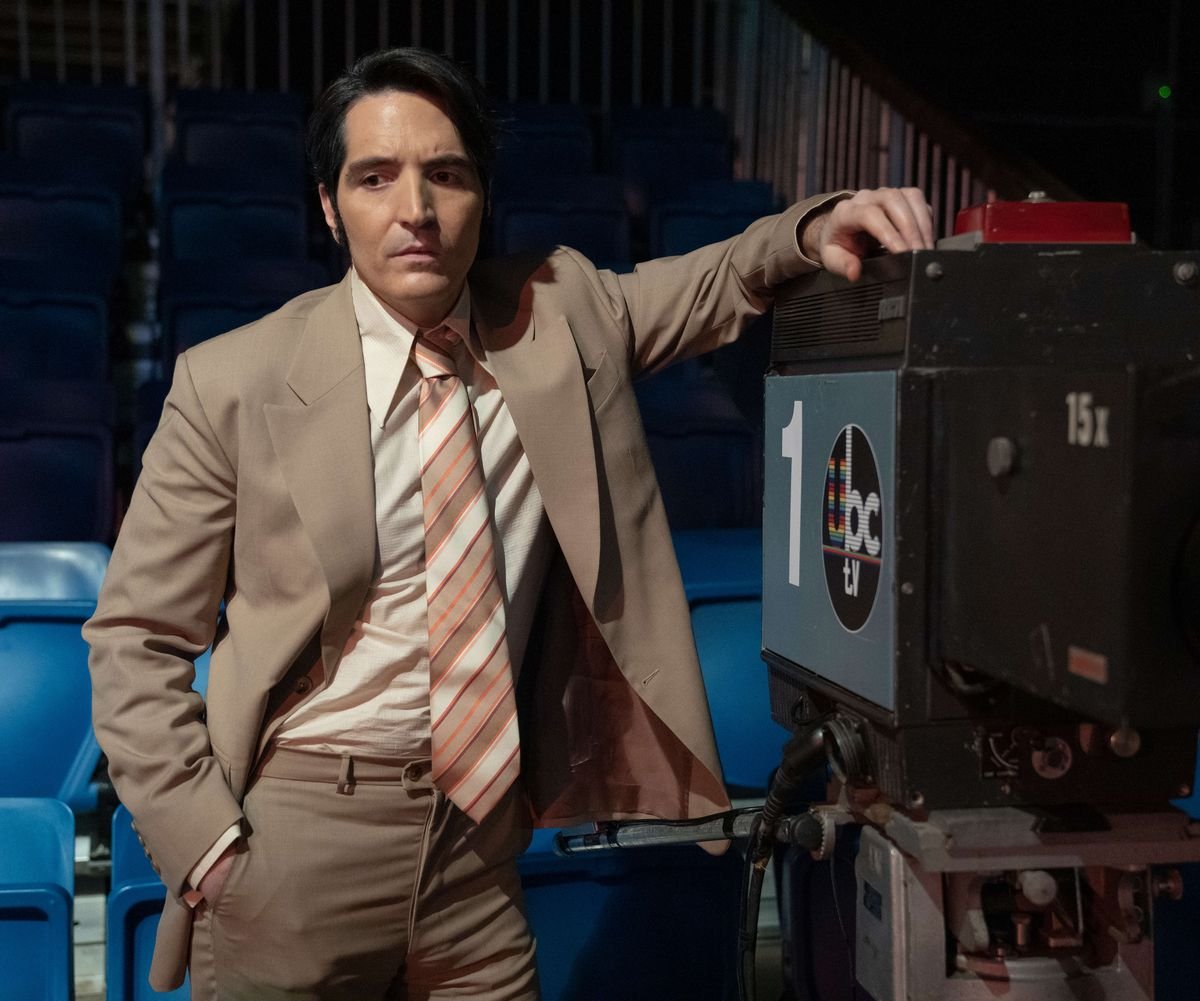 David Dastmalchian as Jack Delroy in Late Night with the Devil wearing a suit and leaning against a camera