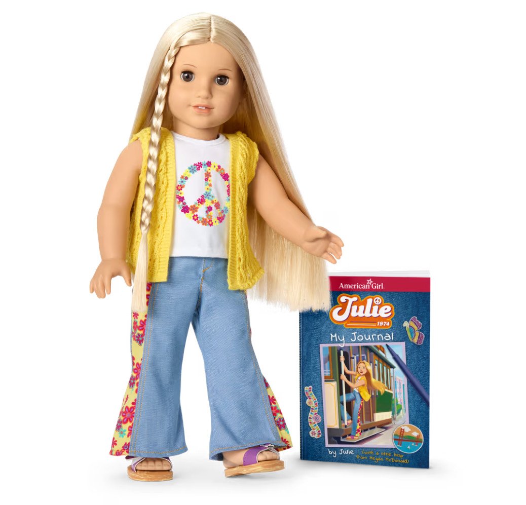 The American Girl doll Julie is shown wearing her character outfit and standing beside her journal.