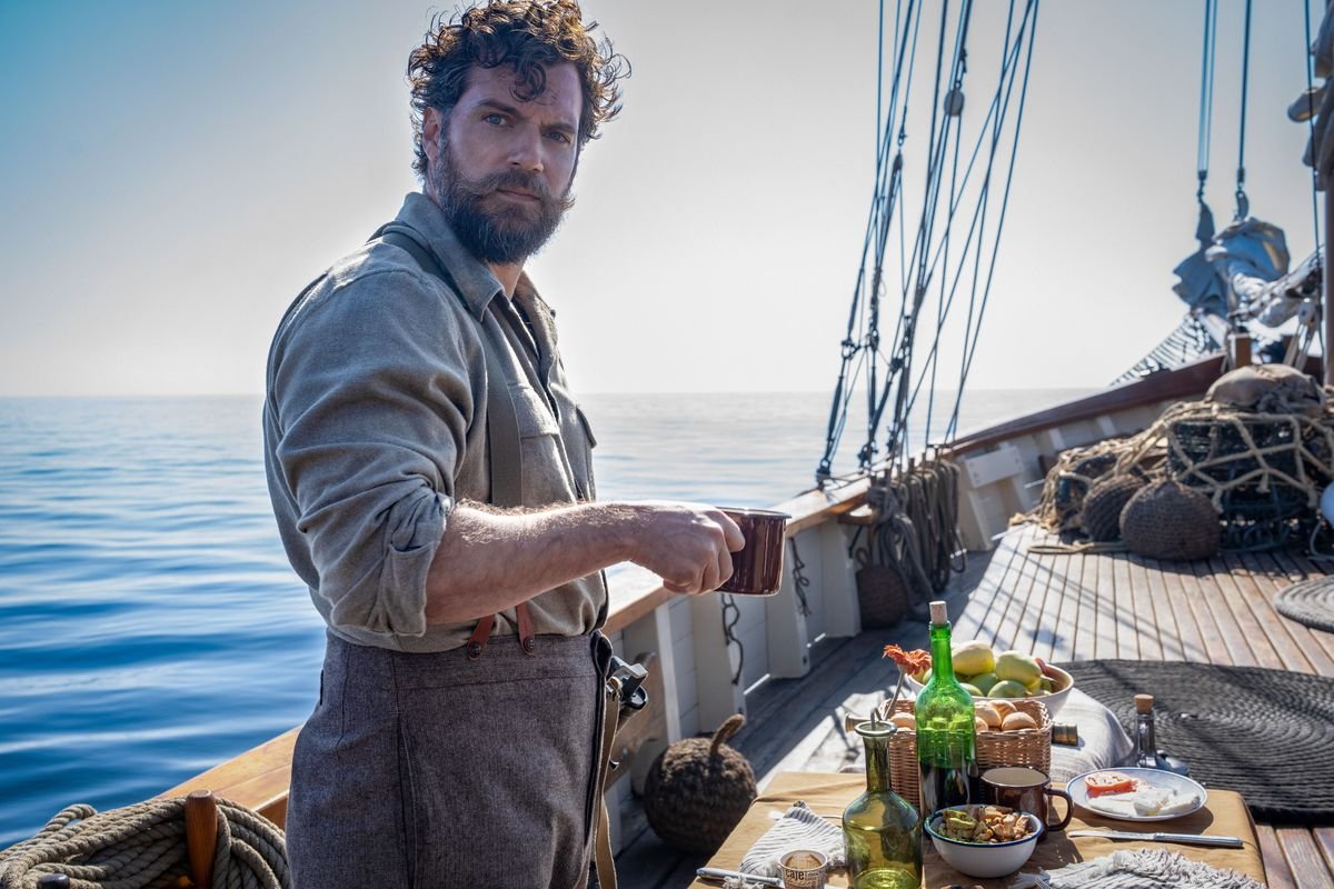 Henry Cavill holds a coffee cup looking puzzled on a boat in The Ministry of Ungentlemanly Warfare