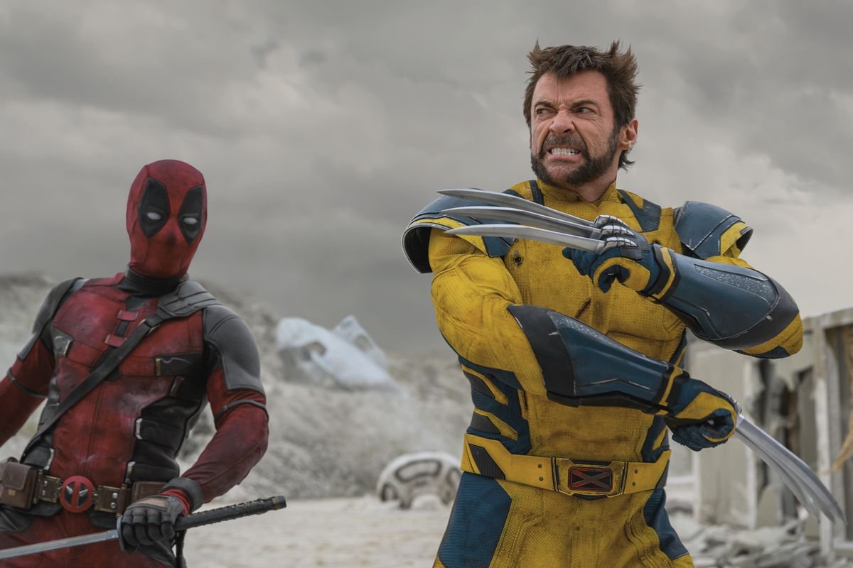 Wolverine pops his claws with his arms across his chest as Deadpool looks on sword in hand in a scene from Deadpool & Wolverine