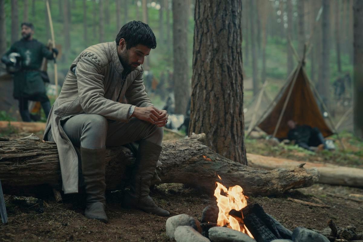 Criston Cole (Fabien Frankel) sitting by a fire